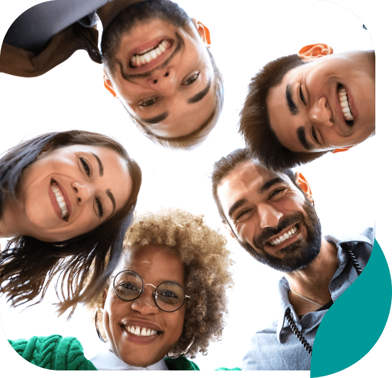 A group of five diverse people stand in a circle, smiling and looking down at the camera against a bright white background.