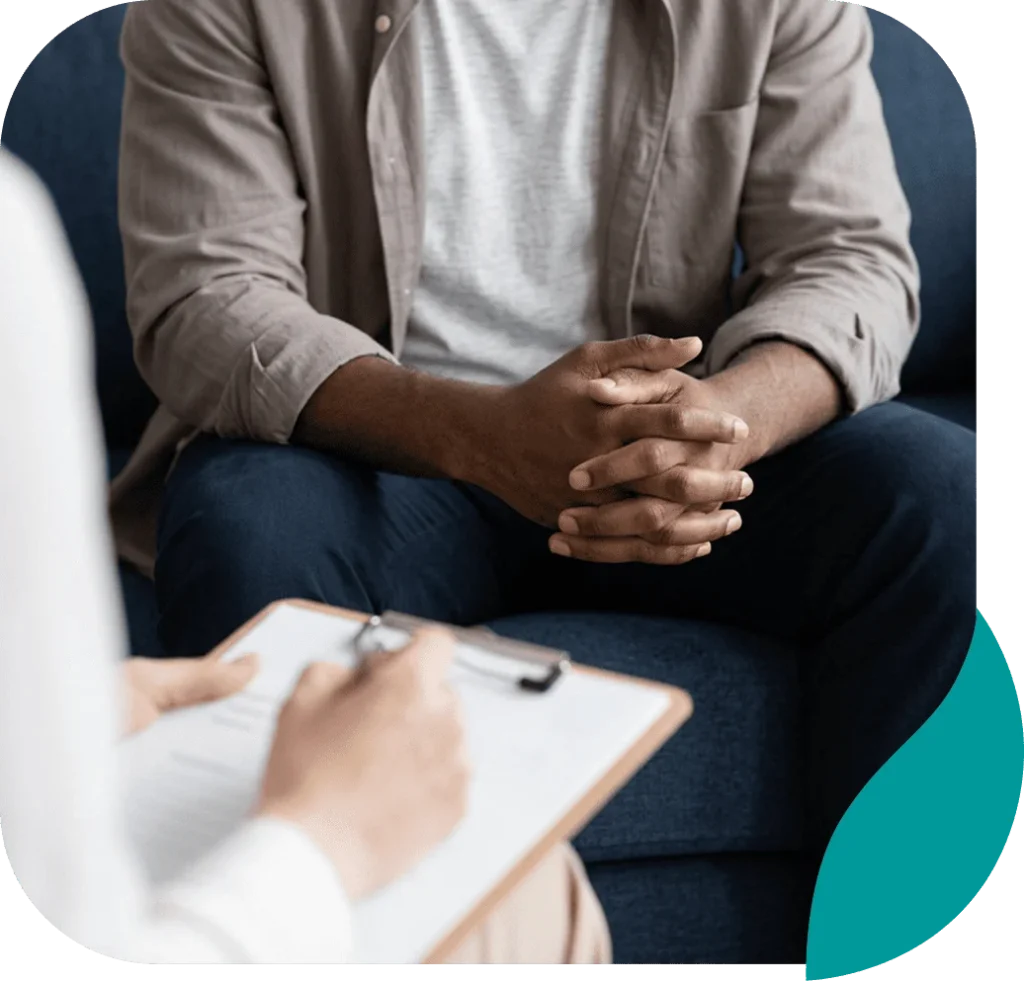 Client with clasped hands during a counseling session as the therapist takes notes