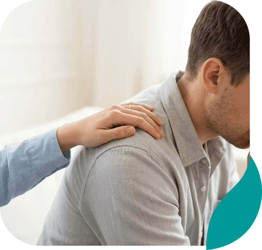 A hand resting on the shoulder of a distressed young man in a show of support
