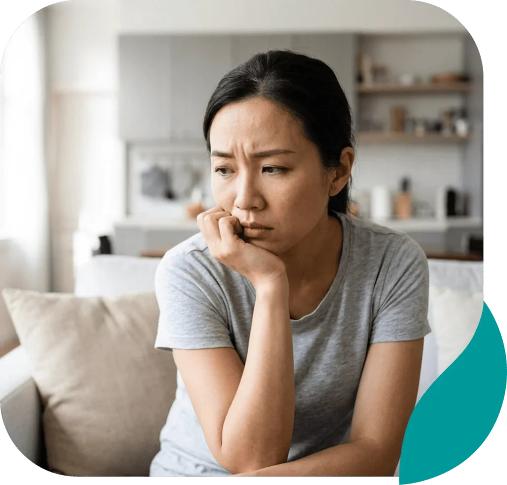 Worried woman sitting on a sofa with her chin resting on her hand